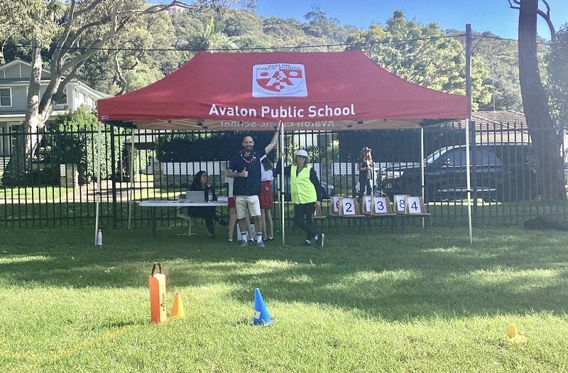 group of people standing under a red custom marquee